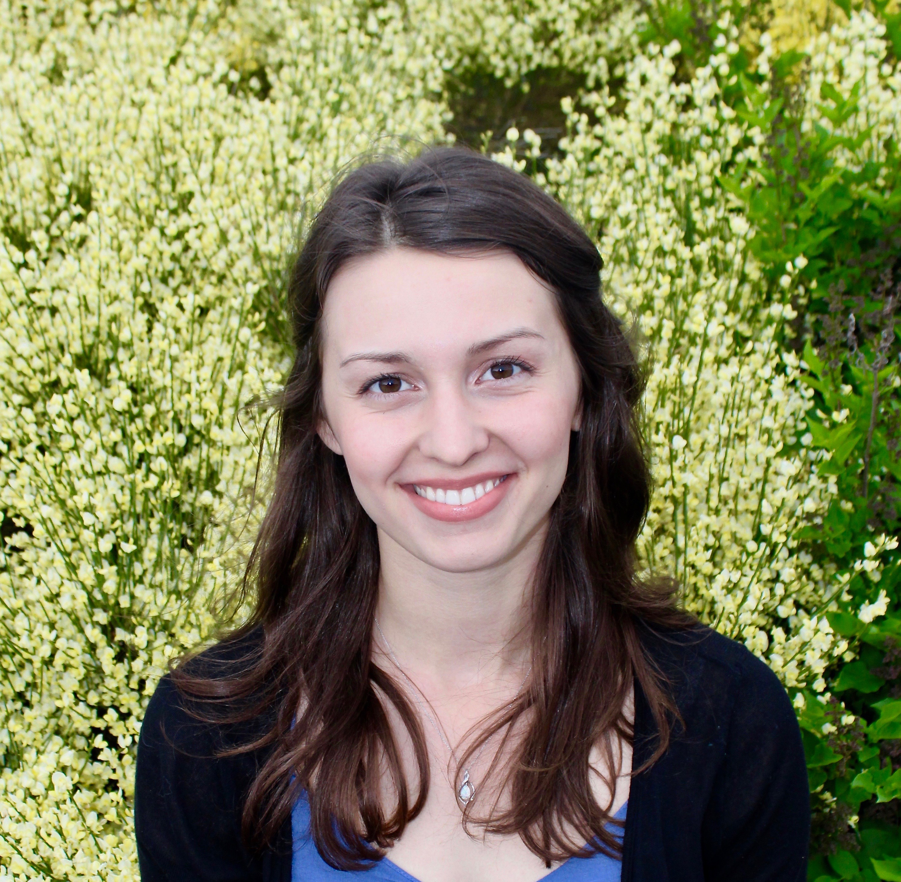 Olga sitting in front of green bushes